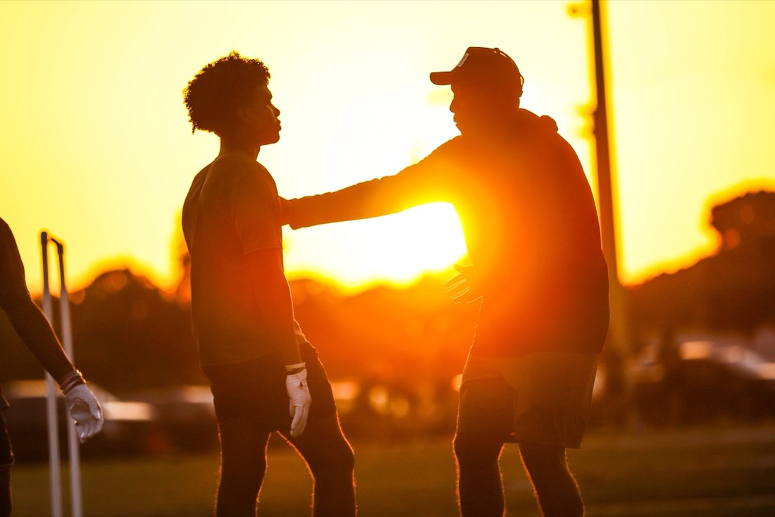 Coach and quarterback silhouetted against the sunset at a QB Stable session